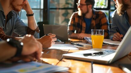 A diverse group of individuals sitting around a table, focused and working on laptops.