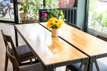 Sunflower in vase on wooden chairs and tables in restaurant or cafe.