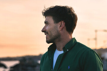 Portrait of a young man in a casual green shirt, captured in profile during the golden hour, with...