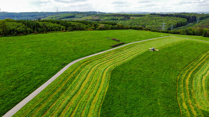 Ein Landwirt mäht mit Traktor eine Wiese (Luftaufnahme)