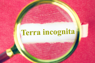 Terra incognita the phrase means unknown land through a magnifying glass under a piece of torn paper