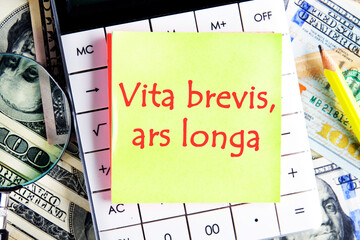 Ars longa, vita brevis ancient Latin saying meaning - Art is long, life is short, on the yellow sticker on the calculator on the background of dollars