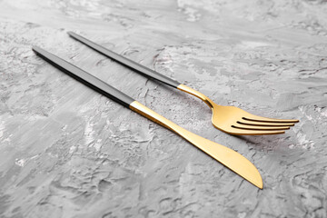 Elegant cutlery. Stylish knife and fork on grey textured table, closeup