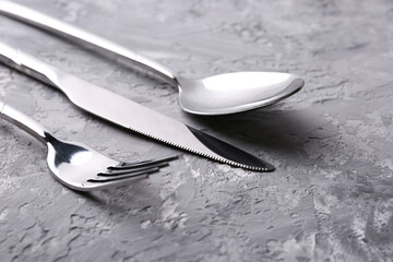 Stylish silver cutlery set on grey textured table, closeup