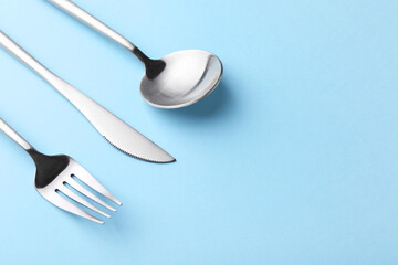 Stylish cutlery set on light blue table, closeup. Space for text