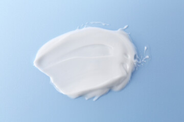 Sample of body care cream on light blue background, top view