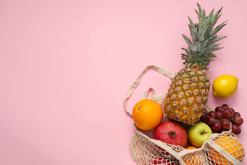 String bag with fresh fruits on pink background, top view. Space for text