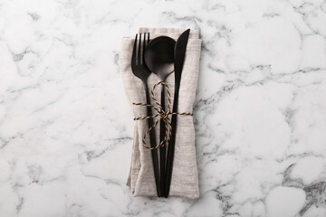Set of stylish cutlery and napkin on white marble table, top view