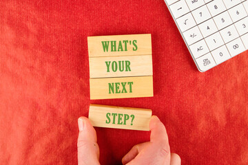 What is your next step symbol text is made up of wooden blocks on a red background