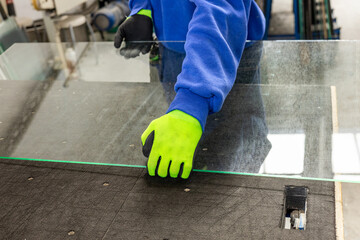 A glazier places sheets of glass on a professional table. Work in a glass factory, specialized...
