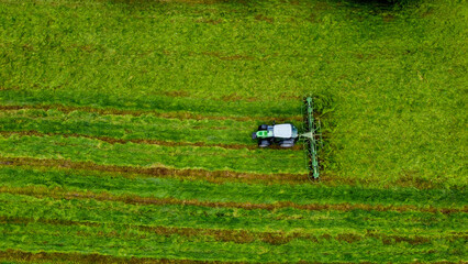 Ein Landwirt wendet mit Traktor das abgemähte Gras (Luftaufnahme)
