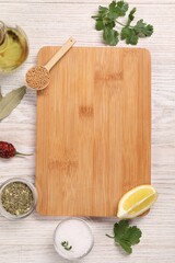 Cutting board, spices and lemon on light wooden table, flat lay. Space for text