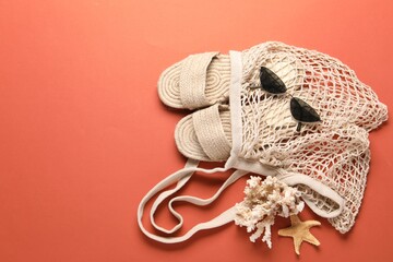 String bag, sunglasses, slippers, starfish and coral on color background, top view. Space for text