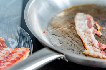 Bacon is fried in a pan. Concept: Junk food rich in cholesterol.