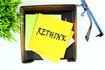 Rethink Business Concept text on a yellow sticker in a stand on a white background, top view