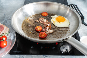 Breakfast in a pan. Delicious scrambled eggs with bacon and cherry tomatoes.