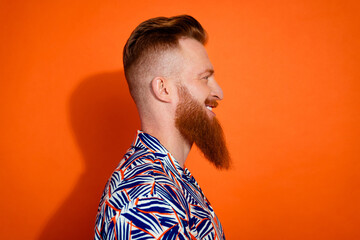 Photo of confident good mood guy dressed print shirt smiling looking empty space isolated orange...