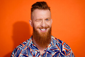 Photo of cheerful funky guy dressed print shirt smiling winking eye isolated orange color background
