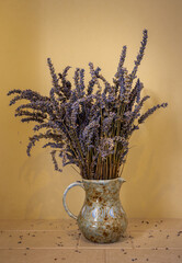 Dried lavender in a jug. With yellow wall and tiled shelf. Portrait orientation.