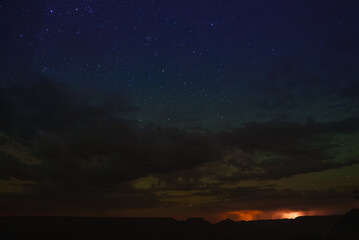 Serene night sky with numerous bright stars over a canyon or desert landscape. Dramatic contrast...