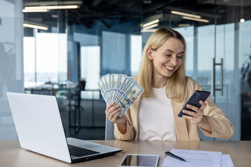 Successful businesswoman holding money while using smartphone