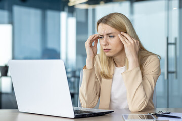 Stressed young woman working intensely on laptop at office