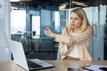 Businesswoman experiencing hand pain at modern office desk