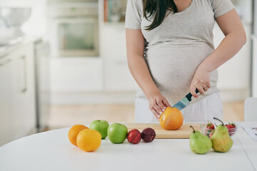 Woman, pregnant and cutting fruit in home, nutrition and vitamin for growth of baby. Female person,...