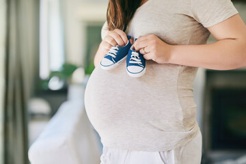 Pregnant, woman and shoes on belly in home for reveal of boy gender with blue color, journey and...