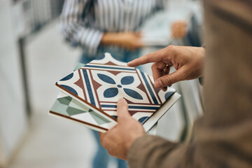 Close-up photo of a male seller holding some samples of ceramic tiles.