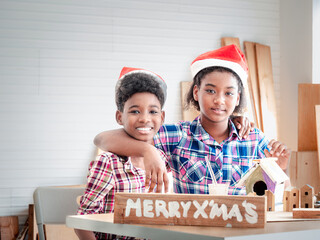 Two African American brothers and sisters help each other make wooden signs to celebrate the...