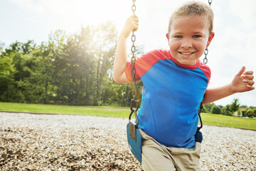 Portrait, nature and child on swing in park for fun, adventure and play time on holiday or weekend...