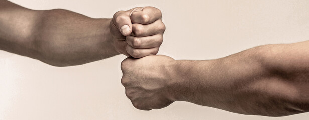 Male athletes fist bumping against a grey background. Friends greeting. Teamwork and friendship....