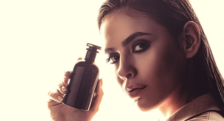 Womans with perfum bottle. Beautiful girl using perfume. Woman with bottle of perfume. Woman presents perfumes fragrance. Woman holding a perfumes bottle