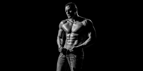 Elegant, masculine, muscular body. Muscular model sports young man on dark background. Sexy torso. Male flexing his muscles. Sport workout bodybuilding concep. Black and white