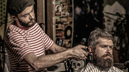 Hairdresser cutting hair male client. Man with beard and mustache in hairdressers chair. Barbershop...