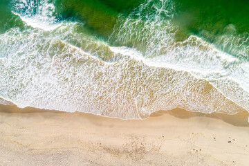 directly above aerial drone view of the shore of a empty beach at sunrise