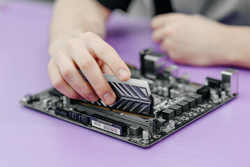 system administrator installing random access memory into motherboard, assembling PC of different accessories or components, close-up view of hands, computer repair and maintenance concept