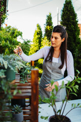 One young caucasian woman is taking care of her plants using plant mister and water can	