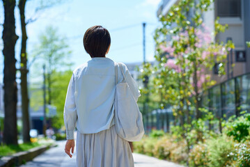 ショッピングバッグを持って街を歩く女性の後ろ姿