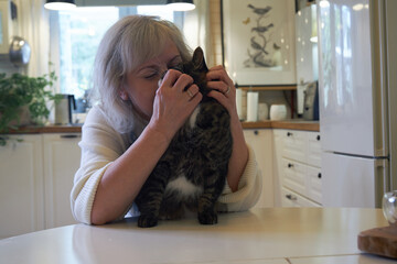 blonde woman in the kitchen playing with a cat