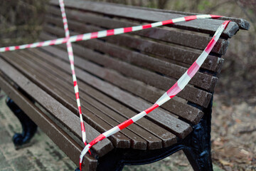 Park bench under rain marked off with red and white caution tape