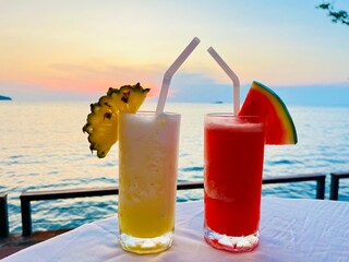 Glass of watermelon juice and Pineapple Juice Smoothie blurred sea background.