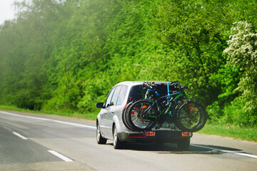 Back view of the modern family car with mounted bike tail carrier on the highway.