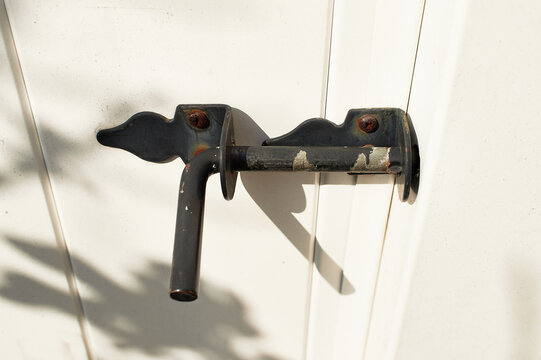 rusted metal latch with peeling paint on an old plastic garden gate door
