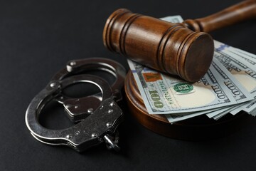 Judge's gavel, money and handcuffs on black background, closeup