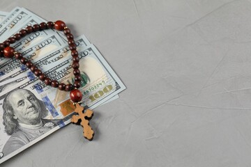 Wooden cross and money on grey table. Space for text