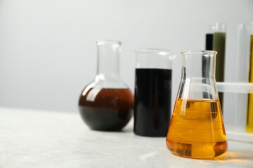 Laboratory glassware with different types of oil on white table, closeup. Space for text