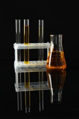 Laboratory glassware with different types of oil on black background