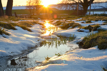 A snow covered field with a stream of water running through it